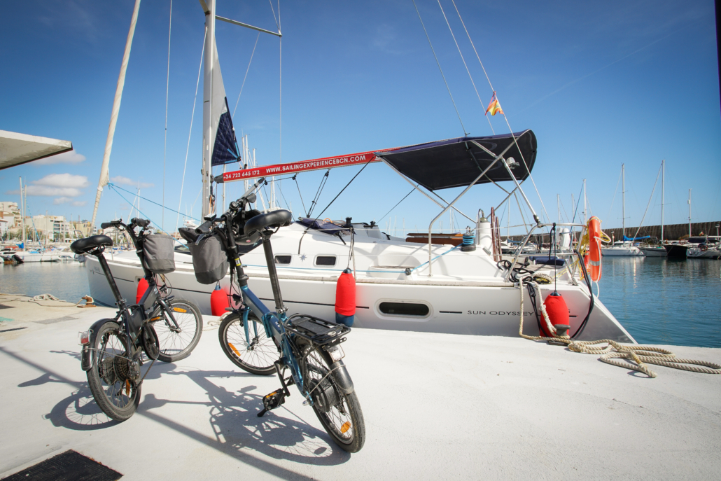 Two e-bikes parked in front a sailing uyacht at the port of Masnou, near Alella